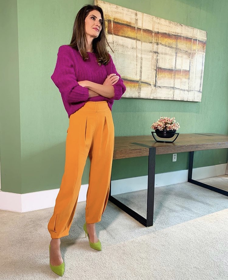 Isabella Fiorentino usa cores tríades na blusa roxa calca laranja e sapato verde limao