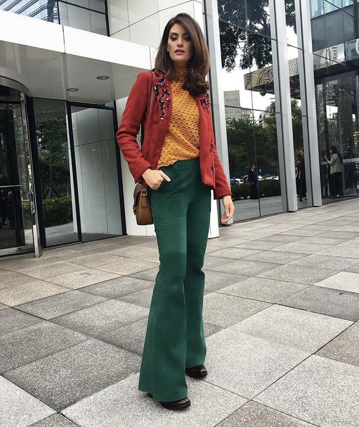 Isabella Fiorentino usa cores tríades no casaco vermelho blusa amarela e calca verde