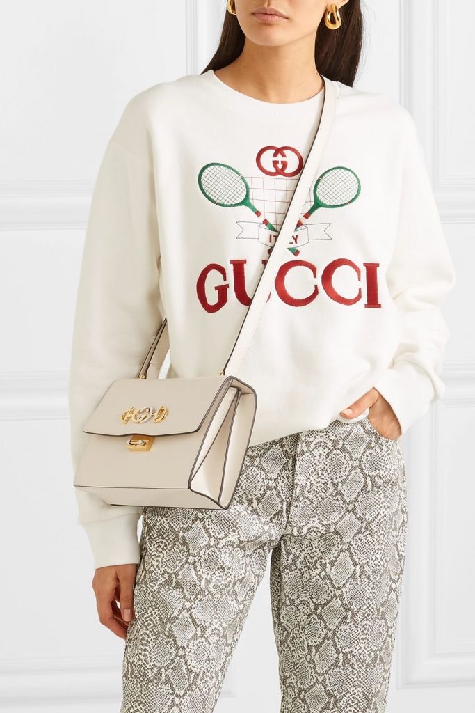 Mulher usa um dos modelos de bolsas transpassado branca com tricot Gucci